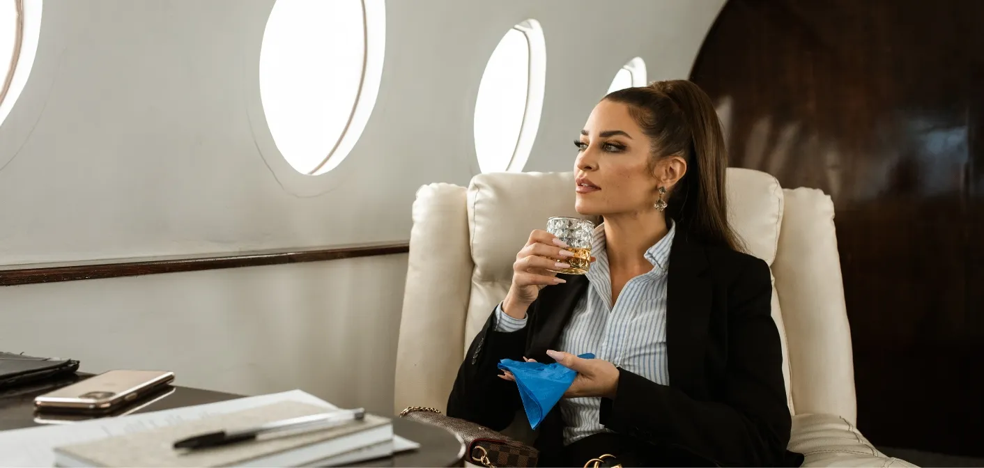 Passagère à bord d'un jet privé, un verre à la main, pendant le vol